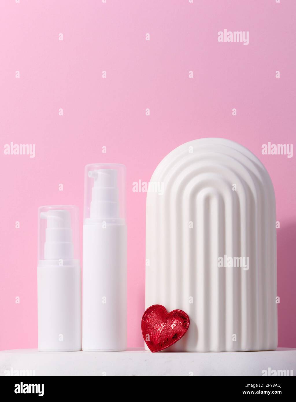 Una vasca di plastica bianca con dispenser è posta su un supporto in marmo e un arco decorativo in ceramica, contenitore cosmetico Foto Stock