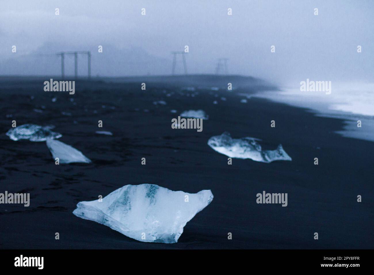 Primo piano piccoli pezzi di ghiaccio sulla sabbia nera concetto foto Foto Stock