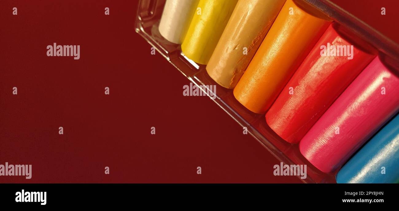 Nuova plasticina multicolore in confezione di plastica su sfondo rosso. Lastre di plasticina di colore rosso, rosa, verde, bianco, giallo, marrone, blu, nero. Set per la creatività dei bambini Foto Stock