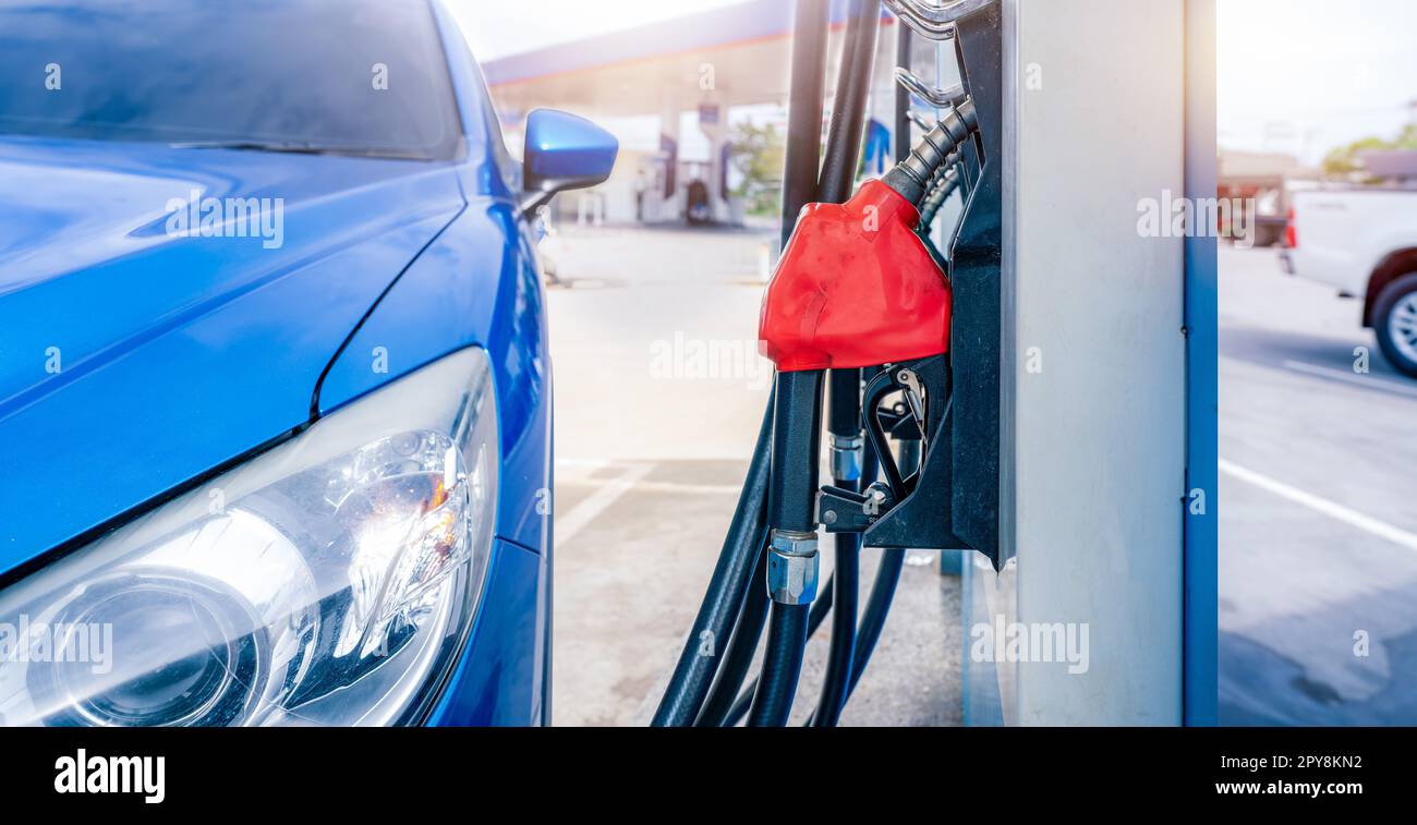 Rifornimento di SUV blu di lusso presso la stazione di servizio. Rabboccare con benzina. Pistola erogatrice di carburante per il rifornimento della pompa di benzina nella stazione di servizio. Industria della benzina. Concetto di prezzo della benzina e crisi petrolifera. Crisi energetica. Foto Stock