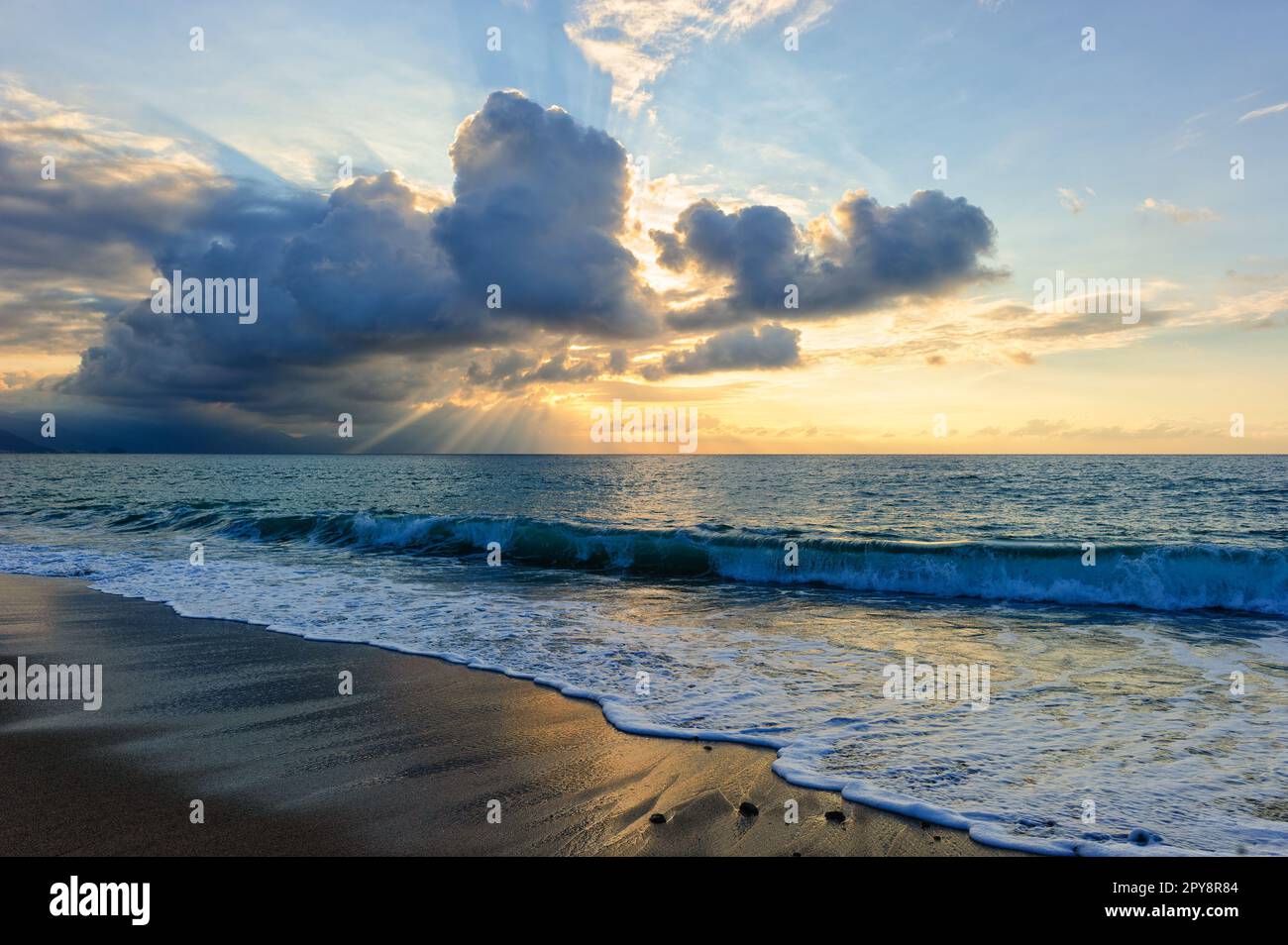 Un tramonto sull'oceano con raggi del sole che emanano da dietro le nuvole Foto Stock