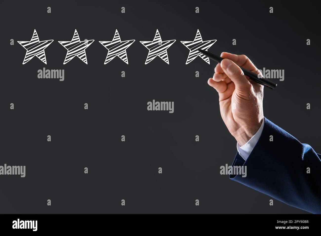 Uomo che indica le icone di cinque stelle su sfondo grigio scuro, primo piano. Valutazione della qualità Foto Stock