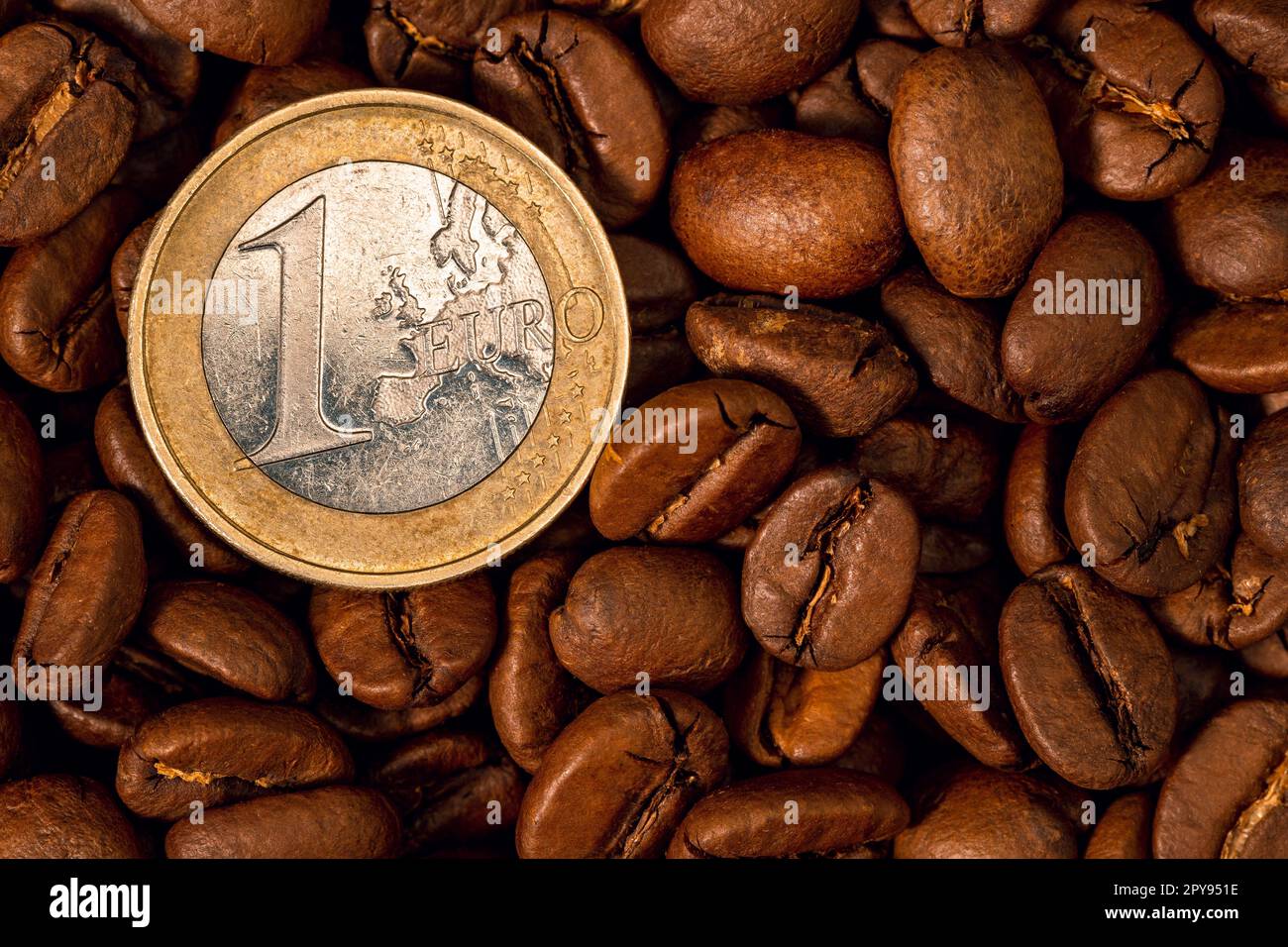 Chicchi di caffè tostati e primo piano con una moneta da un euro Foto Stock