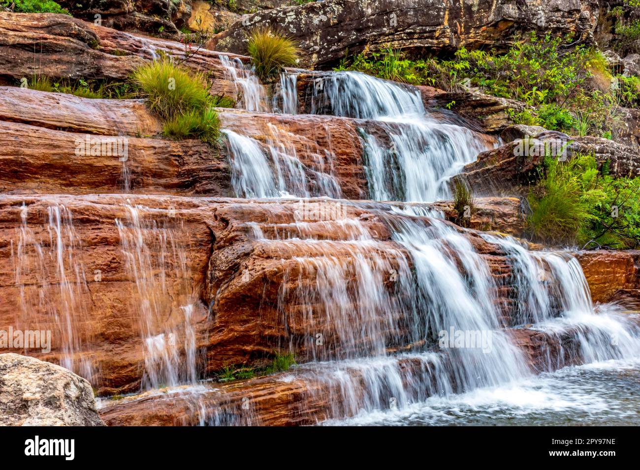 Acqua sfocata sulla bella e piccola cascata tra le rocce e la vegetazione della riserva ambientale Biribiri a Diamantina, Minas Gerais., Brasile Foto Stock