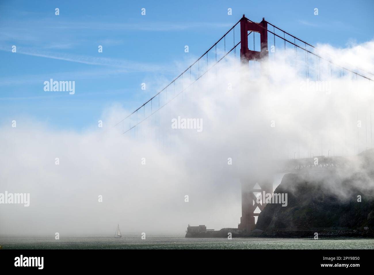 Un piccolo yacht naviga sotto il Golden Gate Bridge a San Francisco mentre la nebbia scorre al largo dell'Oceano Pacifico. Foto Stock