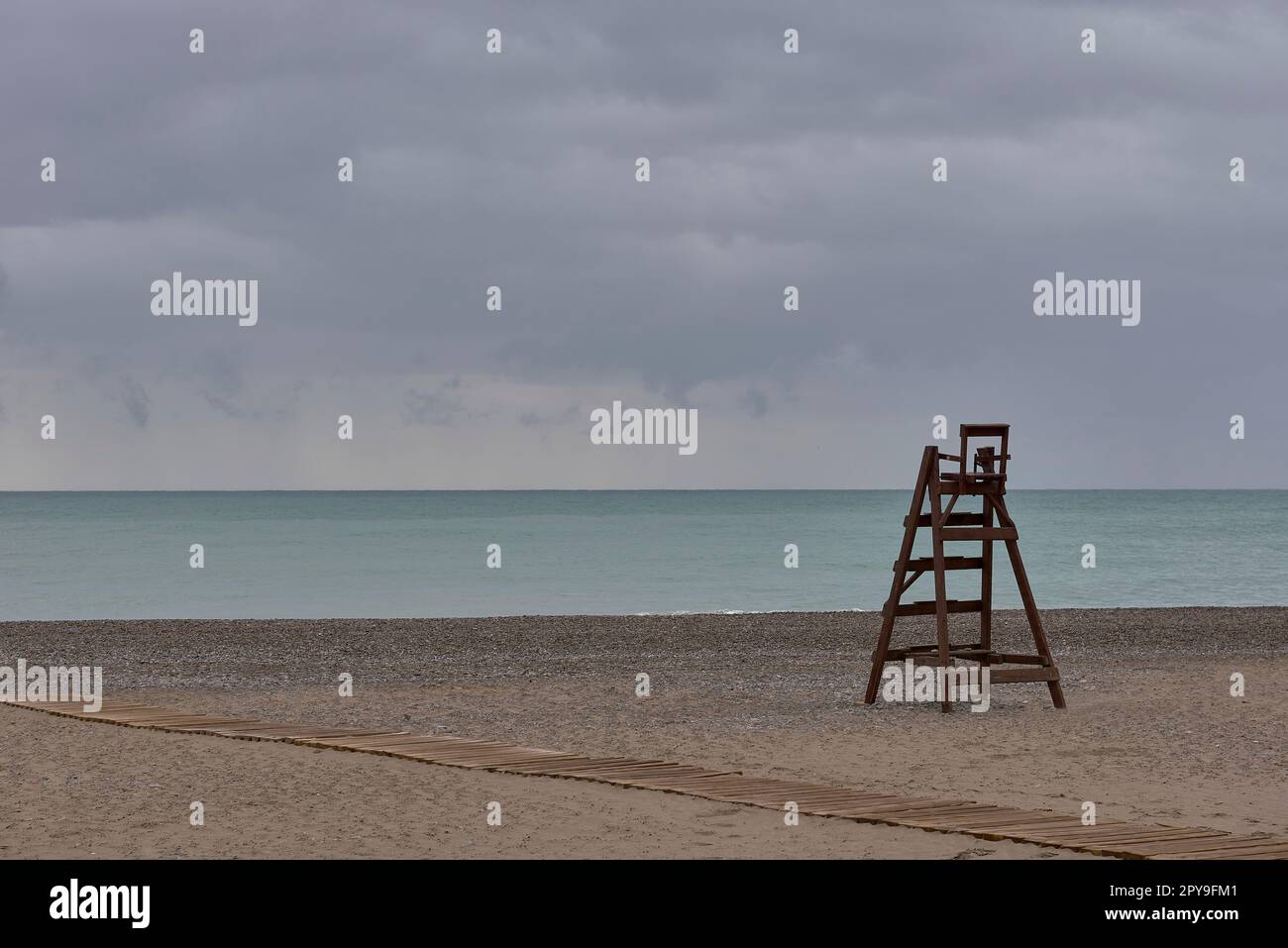 Una sedia bagnino in legno su una spiaggia solitaria Foto Stock