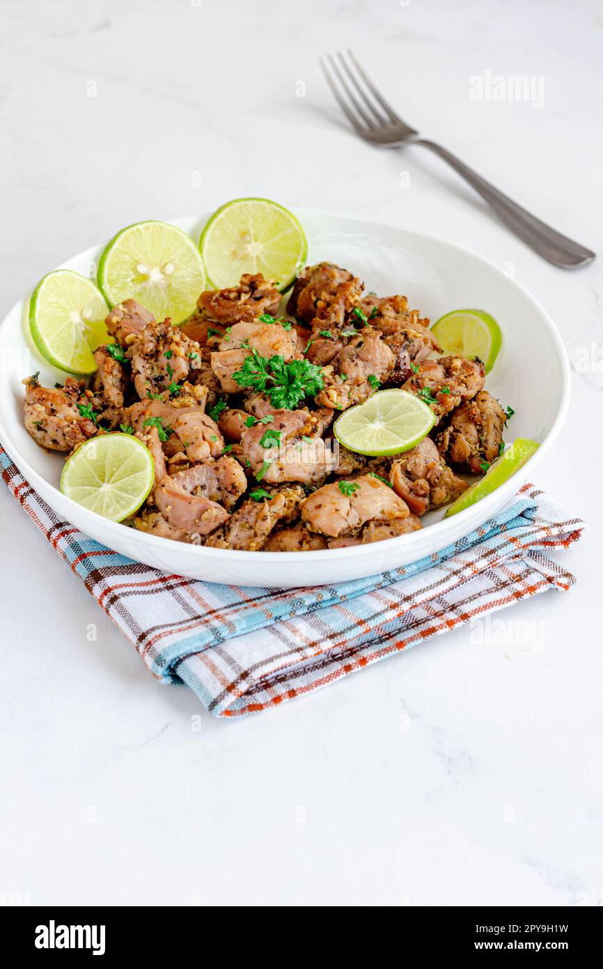 Bocconcini di pollo guarniti con prezzemolo e limone direttamente sopra foto Foto Stock