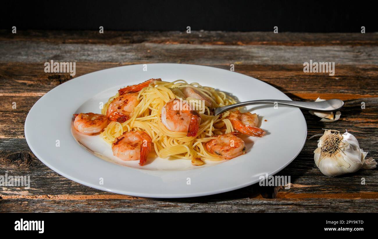 Spaghetti con gamberetti su tavola rustica Foto Stock