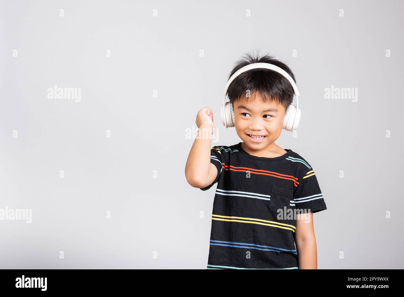 Piccolo simpatico bambino ragazzo di 5-6 anni ascoltare musica in cuffie wireless in studio ripresa isolata. Foto Stock