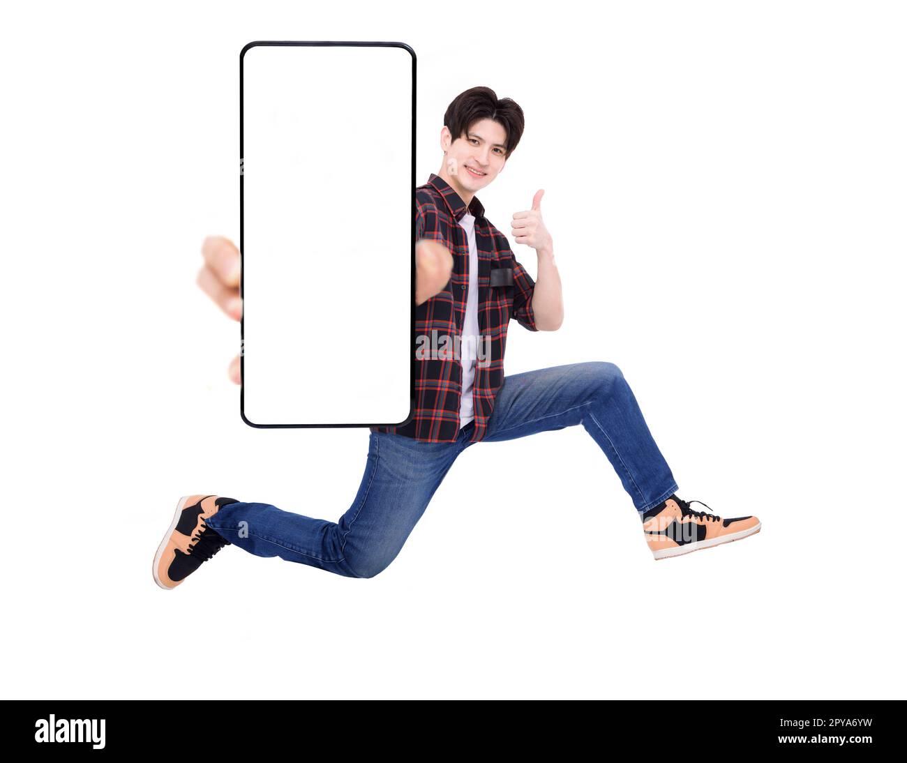Felice giovane uomo che salta e mostra lo schermo vuoto del telefono cellulare Foto Stock