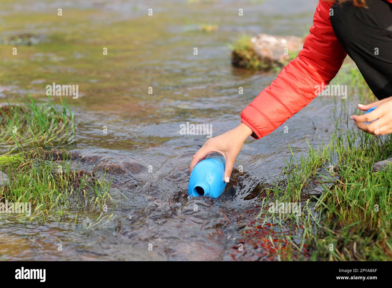 Escursionista che riempie la mensa con acqua non depurata del fiume Foto Stock