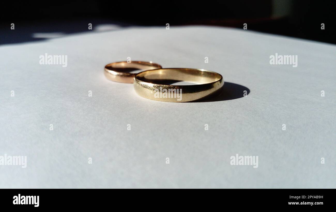 gioielli in oro, due fedi nuziali d'oro su sfondo bianco Foto Stock