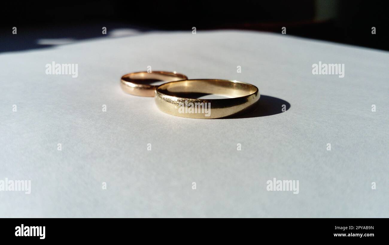 gioielli in oro, due fedi nuziali d'oro su sfondo bianco Foto Stock