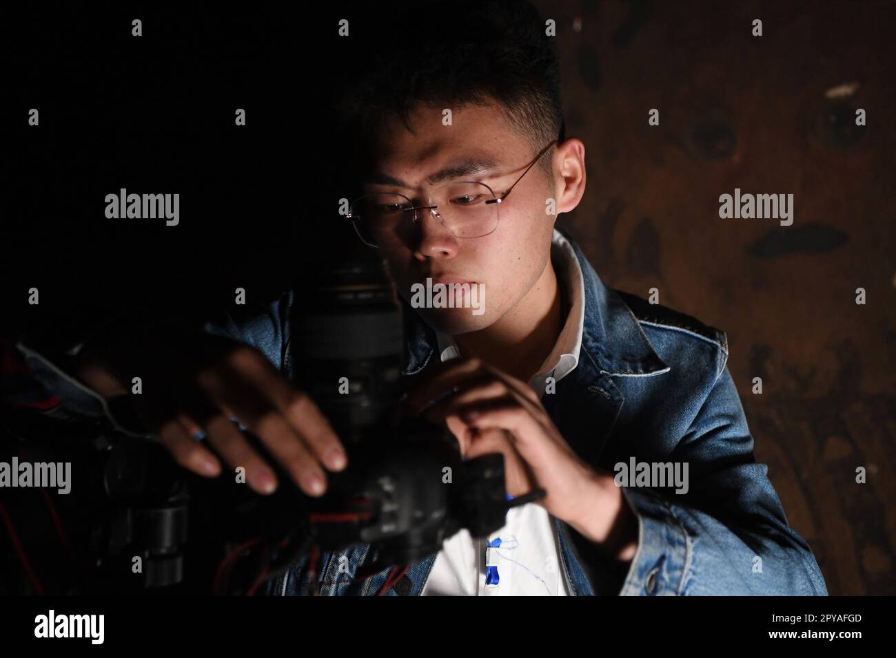 Dunhuang, provincia cinese del Gansu. 25th Apr, 2023. Xiong Yeteng, un tecnico del team di conservazione digitale dell'Accademia Dunhuang, si prepara a raccogliere immagini di murales in una grotta delle grotte di Mogao a Dunhuang, nella provincia del Gansu nella Cina nord-occidentale, il 25 aprile 2023. Un gruppo di giovani tecnici ha cercato di utilizzare la tecnologia digitale per garantire la conservazione permanente e l'uso sostenibile delle reliquie culturali nelle grotte di Mogao, un sito patrimonio dell'umanità dell'UNESCO a Dunhuang. Credit: Fang Xin/Xinhua/Alamy Live News Foto Stock