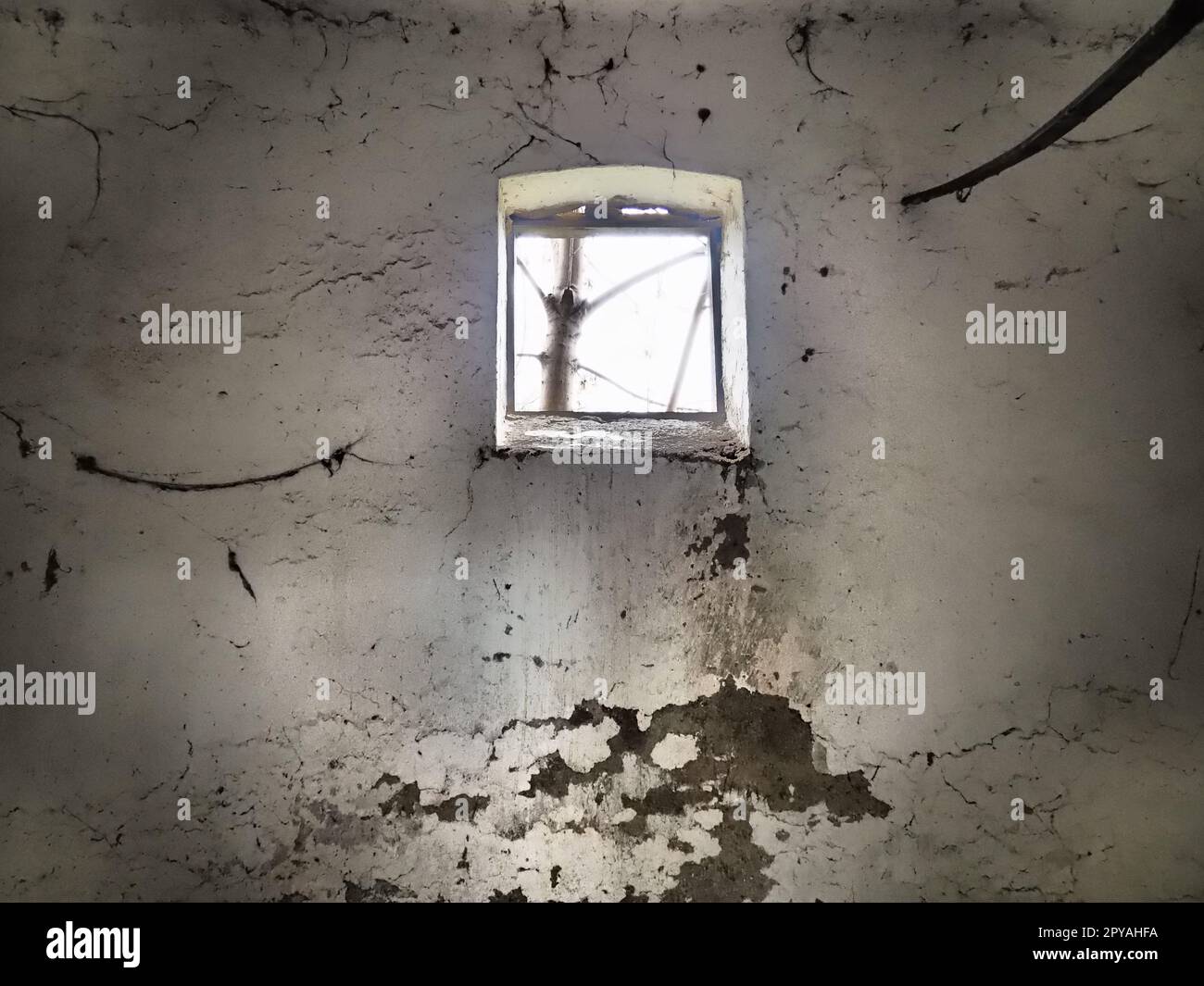 Una piccola finestra in cima al muro. Pareti spaventose con ragnatele. Vecchio dormitorio della chiesa. Halloween o luogo infestato. Cella di prigione con corde di tortura. Visioni e un mondo di allucinazioni Foto Stock