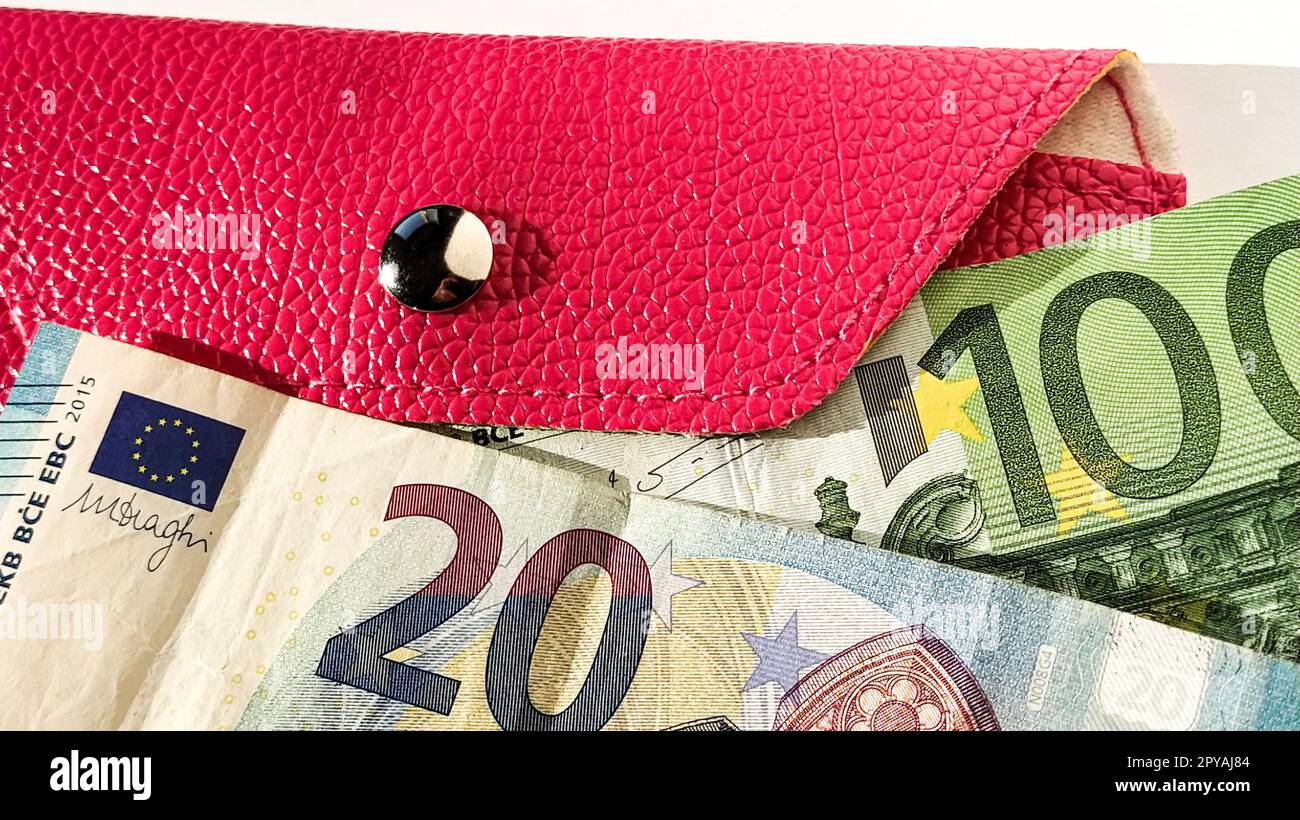 Banconote in euro. Primo piano della moneta europea su sfondo bianco. Portafoglio o borsetta di colore rosa brillante con bottone metallico lucido. Banconote della Banca centrale per 20 e 100 euro Foto Stock