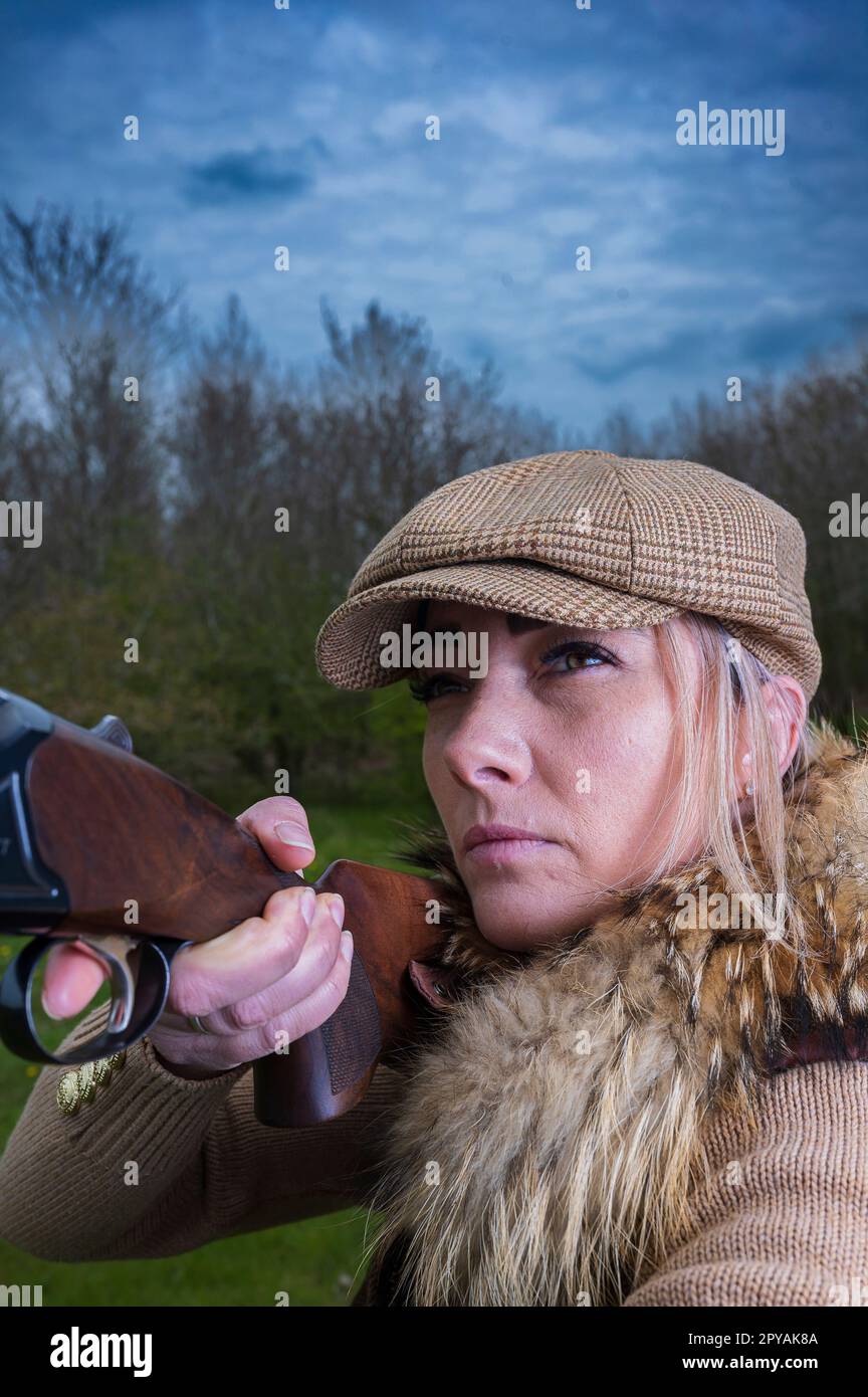 Una donna di oltre trent'anni che spara nei boschi alla luce della sera con un fucile Foto Stock