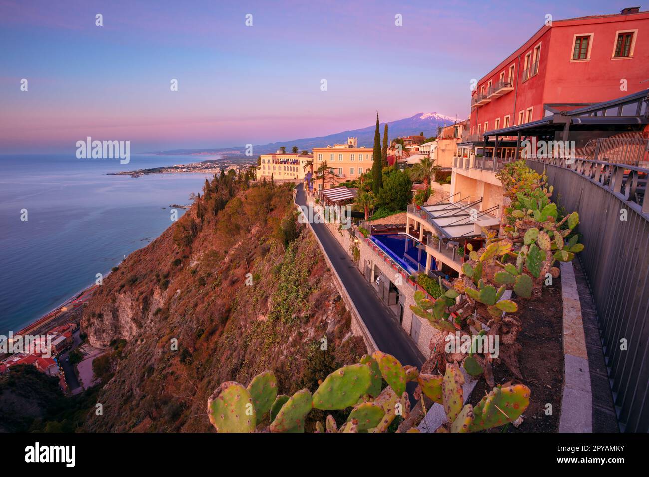 Taormina, Sicilia, Italia. Immagine del paesaggio urbano della pittoresca città di Taormina, Sicilia con il vulcano Mt. Etna sullo sfondo all'alba. Foto Stock