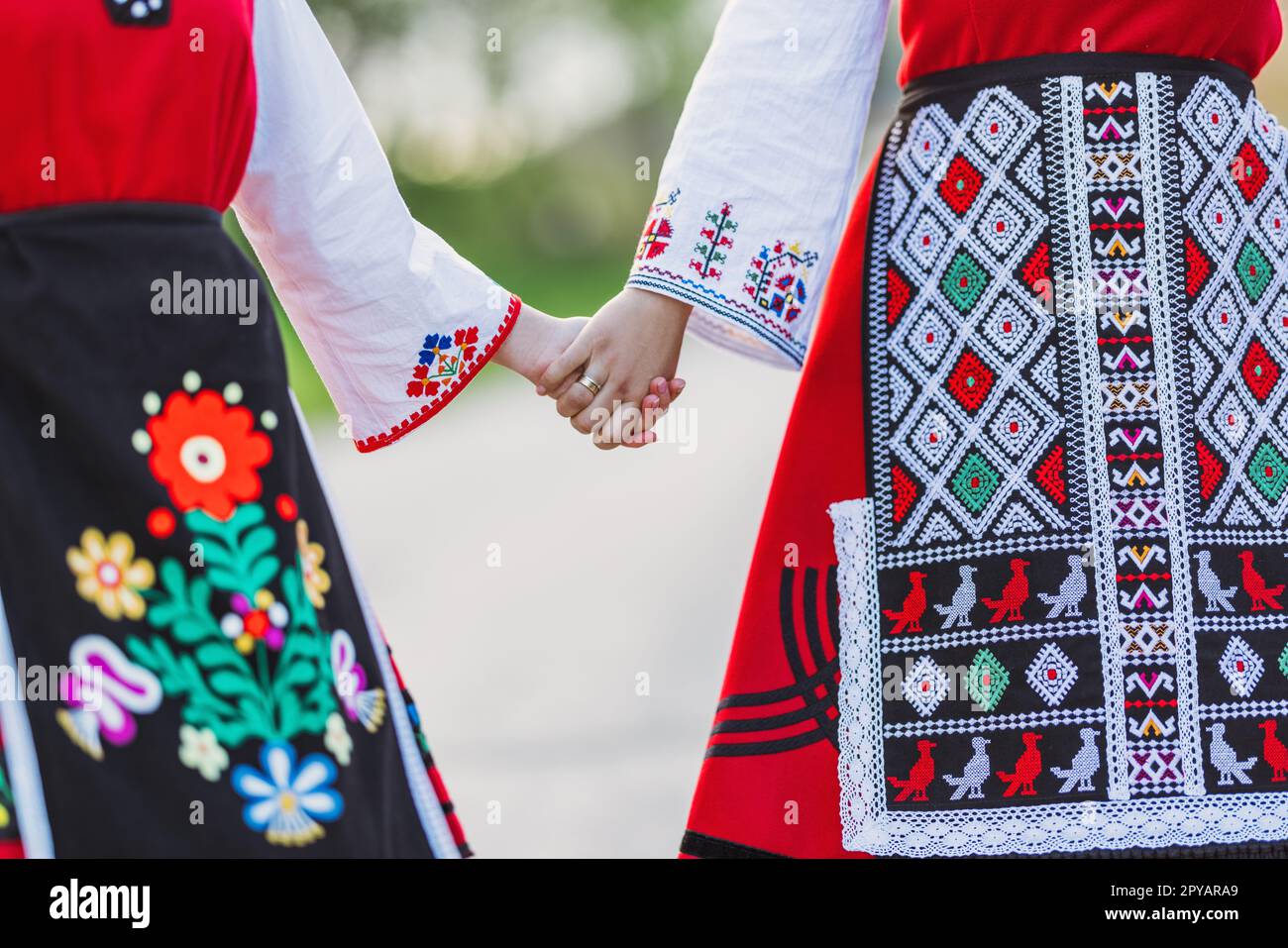 Ragazze in costumi tradizionali etnici bulgari con ricami folcloristici in mano. Lo spirito della Bulgaria - cultura, storia e tradizioni. Foto Stock