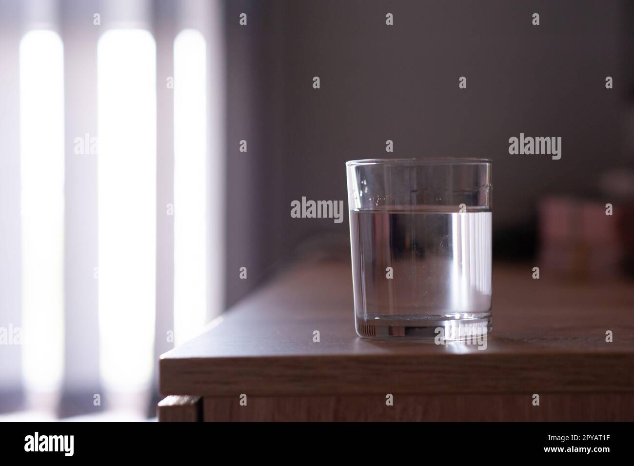 Bicchiere d'acqua sul tavolo in legno in camera. Spazio per il testo Foto Stock