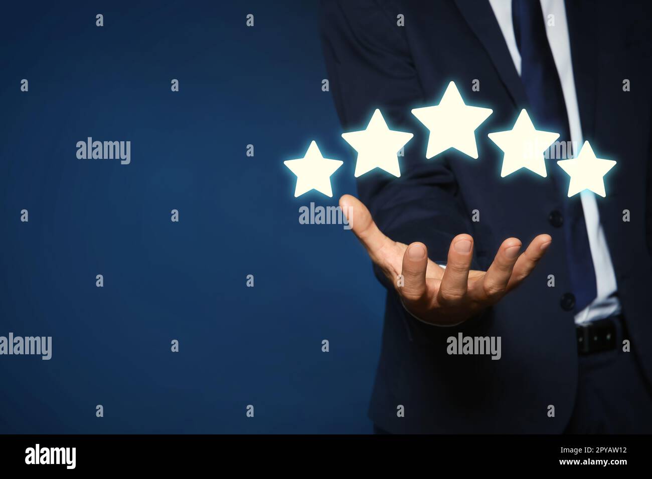 Uomo che mostra icone di cinque stelle su sfondo blu, primo piano. Valutazione della qualità Foto Stock