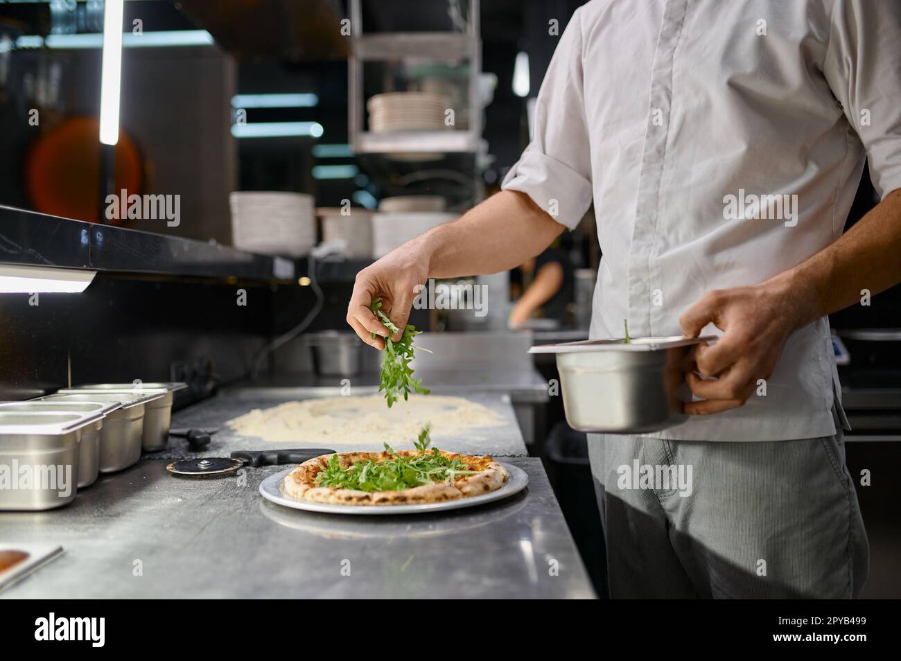 Chef cospargere di verde fresco su pizza tradizionale Foto Stock