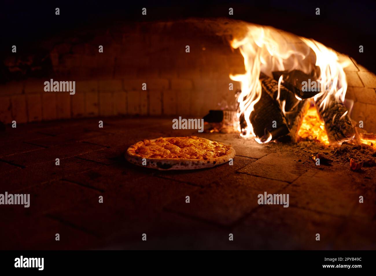 La pizza viene cotta nel tradizionale forno a legna con fuoco aperto Foto Stock