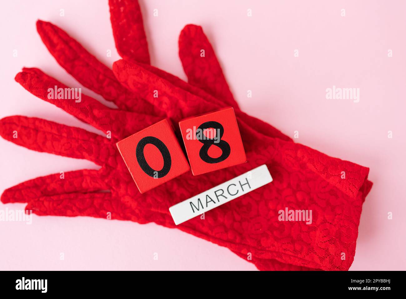 Bellissimi guanti in pizzo rosso sui quali sono cubetti di legno con l'iscrizione 8 marzo. Pronto per le vacanze, Festa della donna. Foto Stock