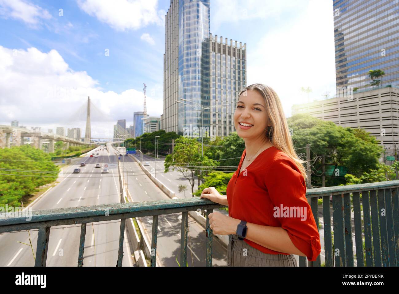 Viaggia a San Paolo, Brasile. Ritratto di una bella ragazza sorridente con paesaggio urbano di San Paolo e Ponte Estaiada sullo sfondo, San Paolo, Brasile. Foto Stock