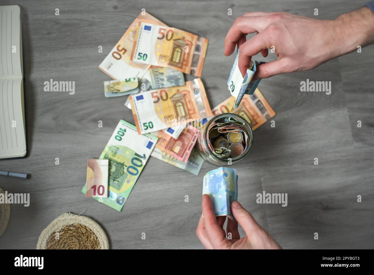 Le mani di un uomo contano le banconote in euro in ufficio, mettendo i soldi in un barattolo di risparmio Foto Stock