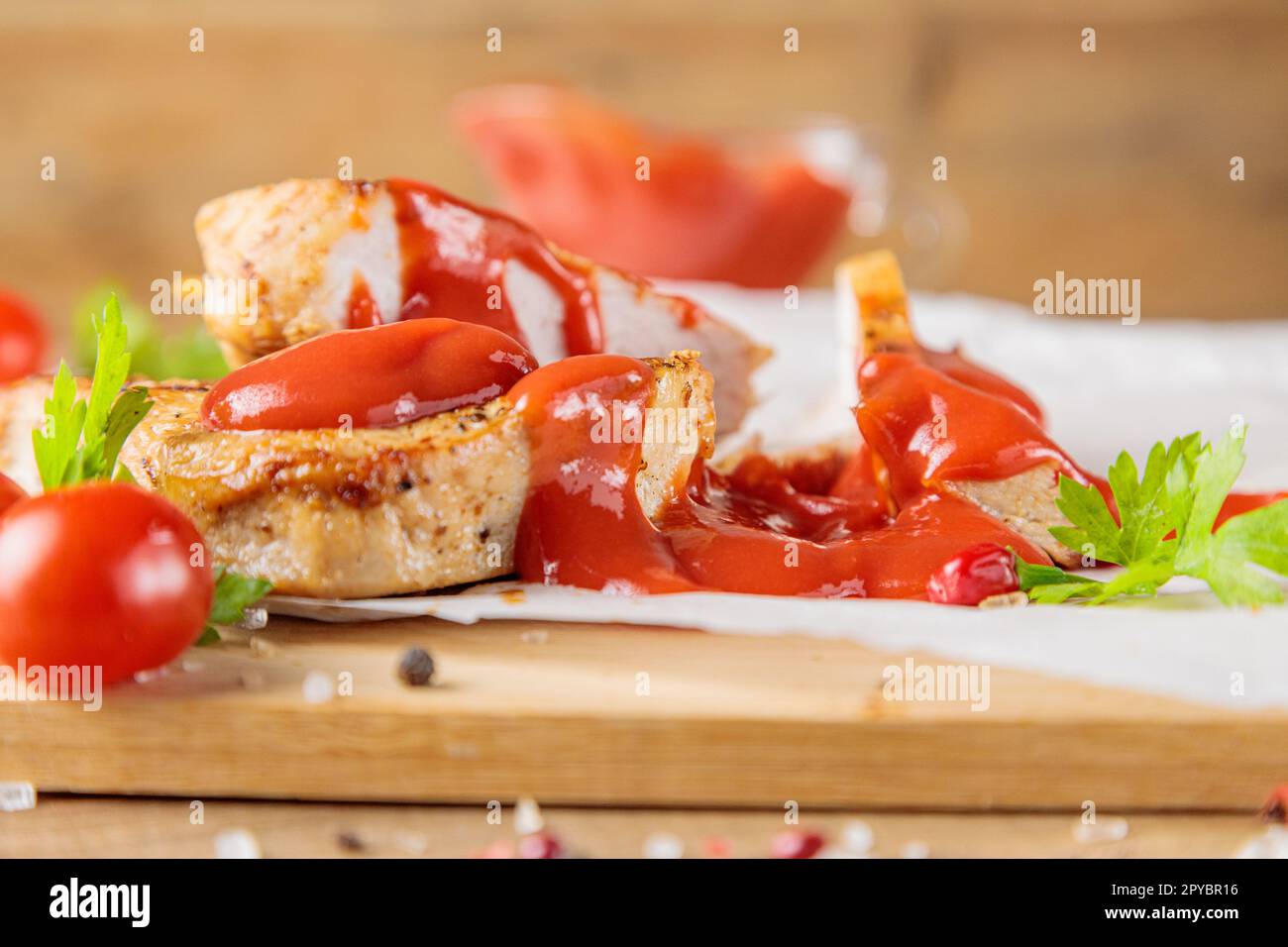 Fette di carne di maiale arrosto con pomodoro e ketchup su un asse di legno Foto Stock