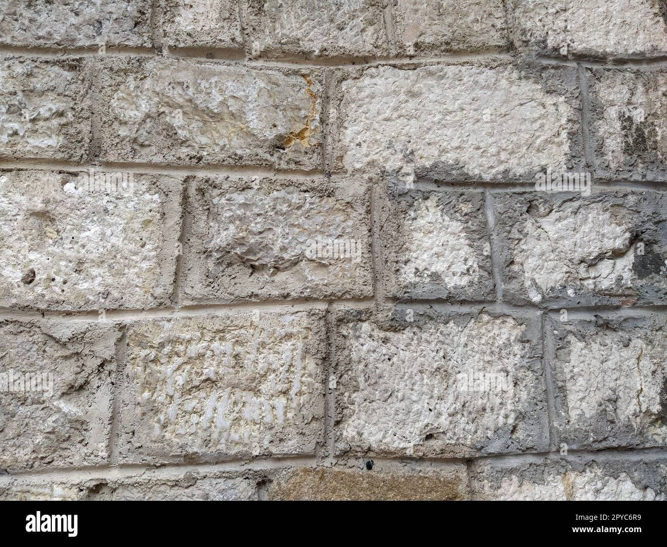 Muratura in pietra invecchiata con le intemperie di una vecchia casa. Antico sfondo murale in mattoni. Vecchi mattoni di pietra graffiati irregolari. Muro dell'edificio turco. Sfondo irregolare di pareti calcaree Foto Stock