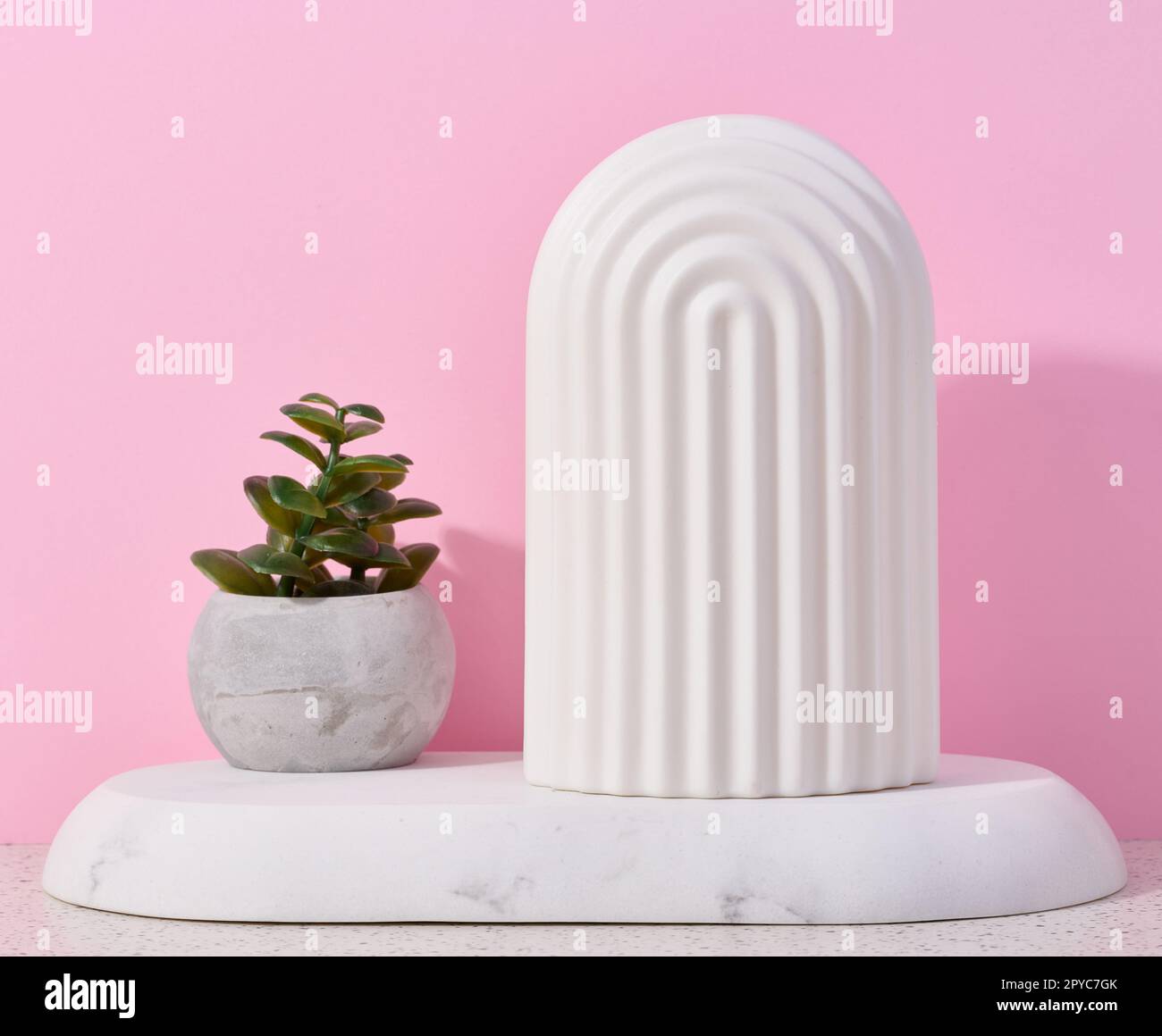 Vaso in ceramica con pianta e arco decorativo bianco sul tavolo. Foto Stock