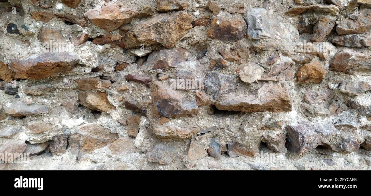Muro di pietra. Grandi ciottoli impilati in colori caldi. Torre a Kula, Serbia. Foto Stock