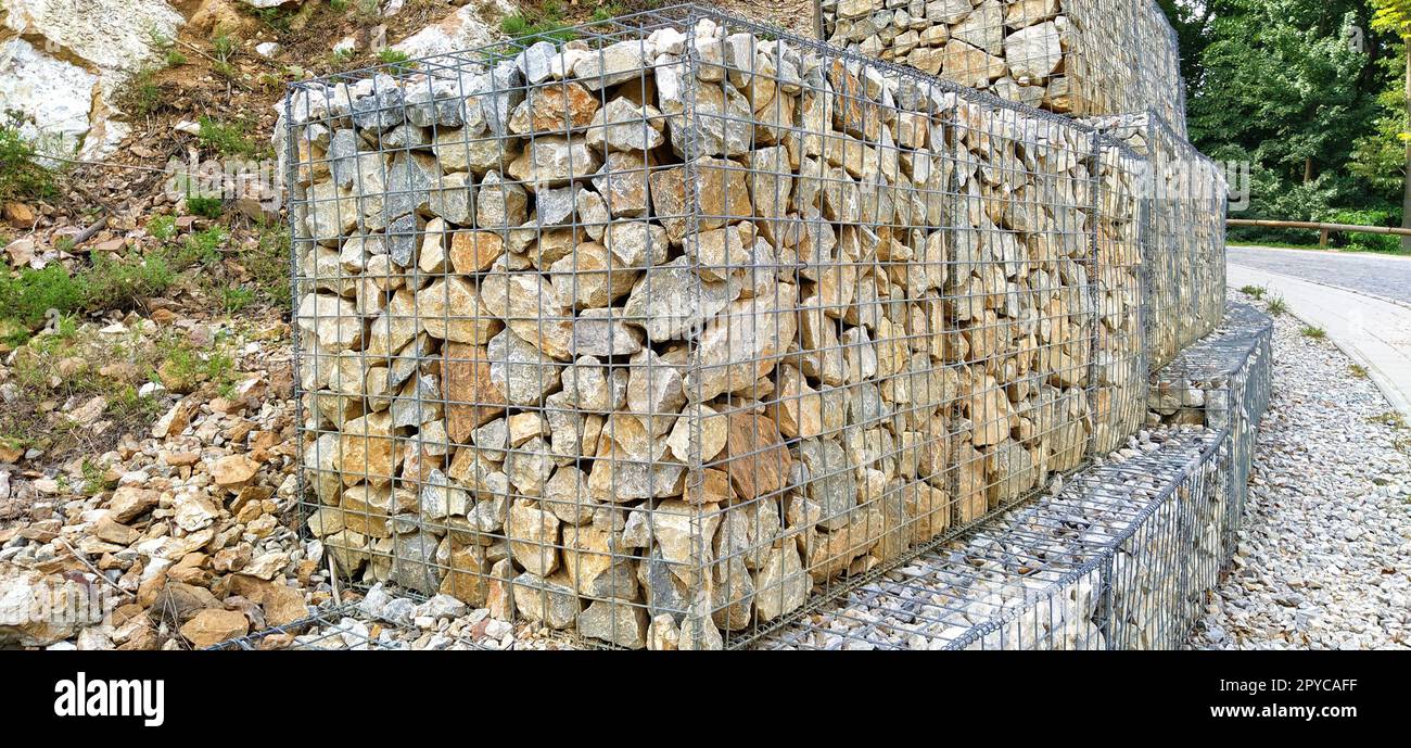 protezione ingegneristica contro i processi di frana e frana nella costruzione di strade. Protezione contro il crollo del suolo e delle pietre sulla strada. Pietre posizionate in telai metallici Foto Stock