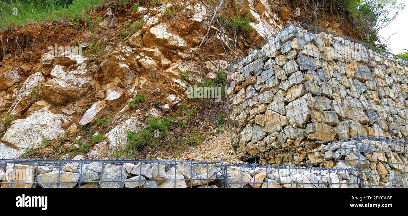 protezione ingegneristica contro i processi di frana e frana nella costruzione di strade. Protezione contro il crollo del suolo e delle pietre sulla strada. Pietre posizionate in telai metallici Foto Stock