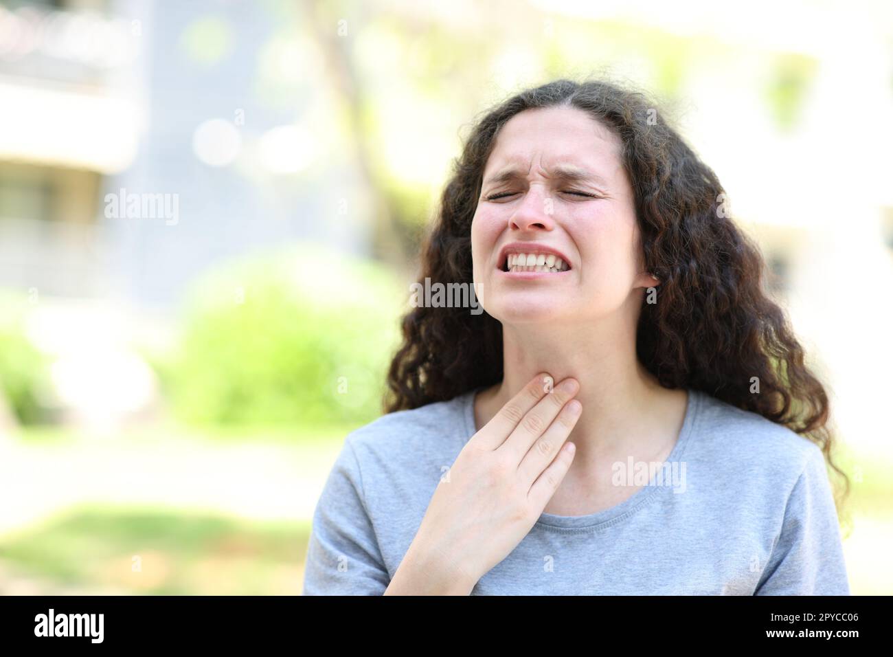 Donna che soffre di mal di gola per strada Foto Stock