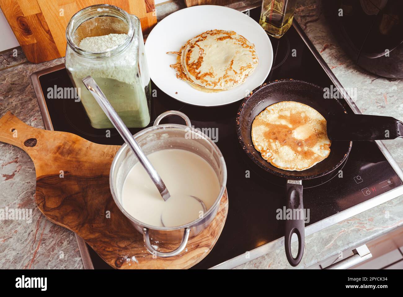 Preparazione di pancake sottili su padella in cucina, con impasto da cuocere per crepes e pancake Foto Stock