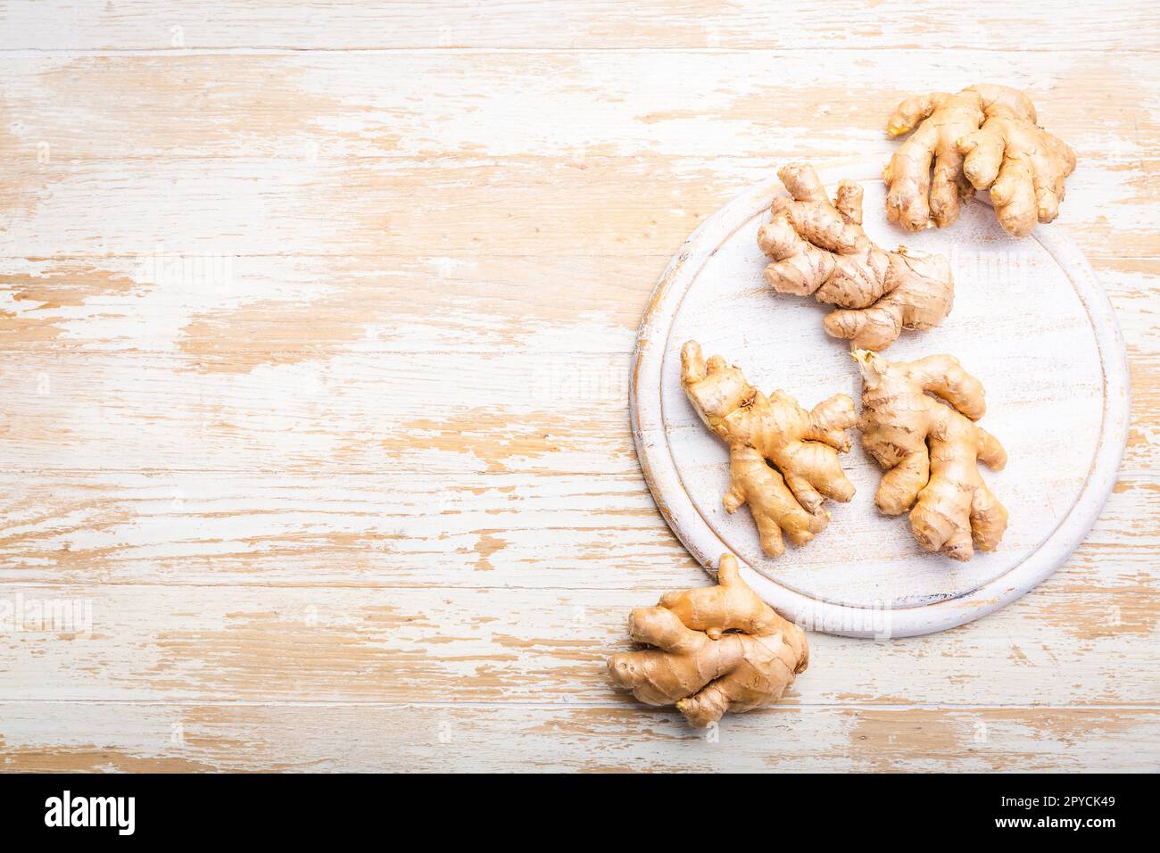 Radici di zenzero fresche e organiche su fondo di legno bianco. Foto Stock