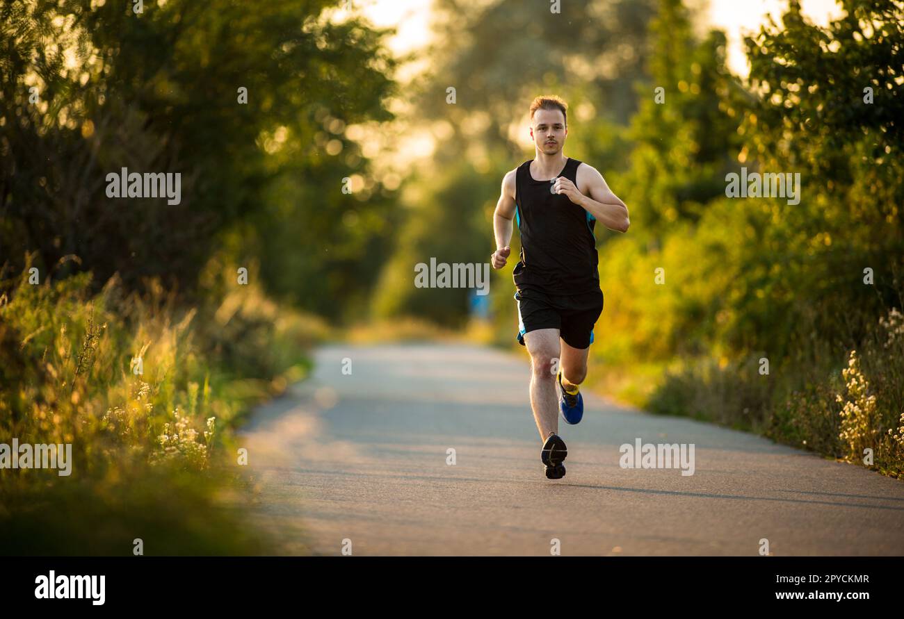 Inquadratura di un giovane atleta maschio training su una pista. Sprinter in esecuzione su piste per atletica visto da sopra. Foto Stock