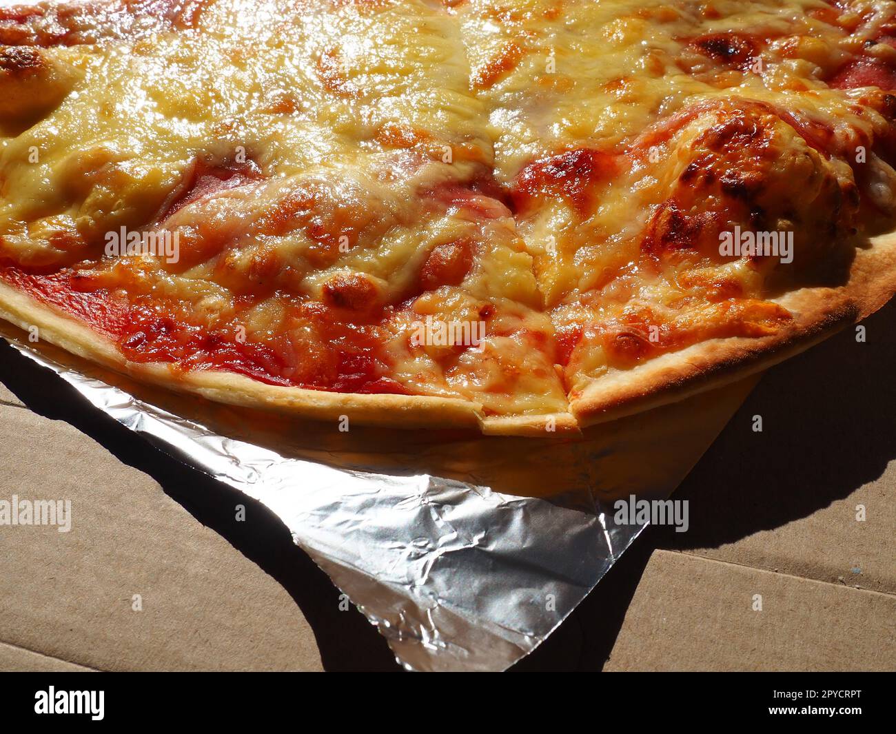 Pizza con pomodori e formaggio in scatola di cartone e foglio di alluminio. Pizza deliziosa da vicino. Consegna del cibo a domicilio tramite corriere. Ordinare la pizza. Torta tradizionale italiana a base di lievito con ripieno Foto Stock