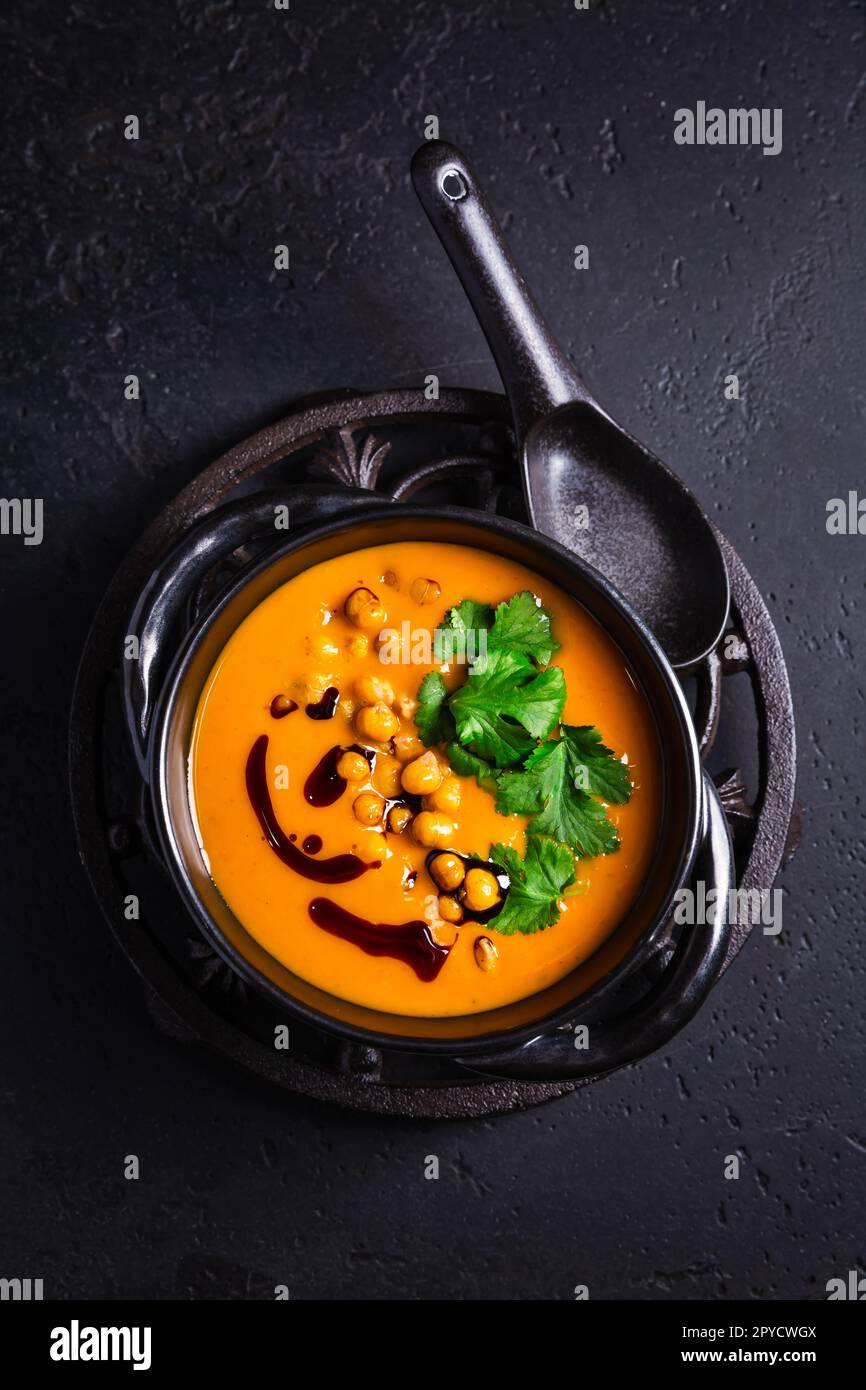 Zuppa cremosa di crema di zucca con olio di semi di zucca, ceci al forno e coriandolo Foto Stock