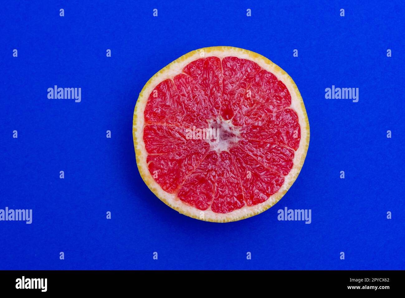 Lato a fette di pompelmo con polpa rossa isolata su fondo blu Foto Stock