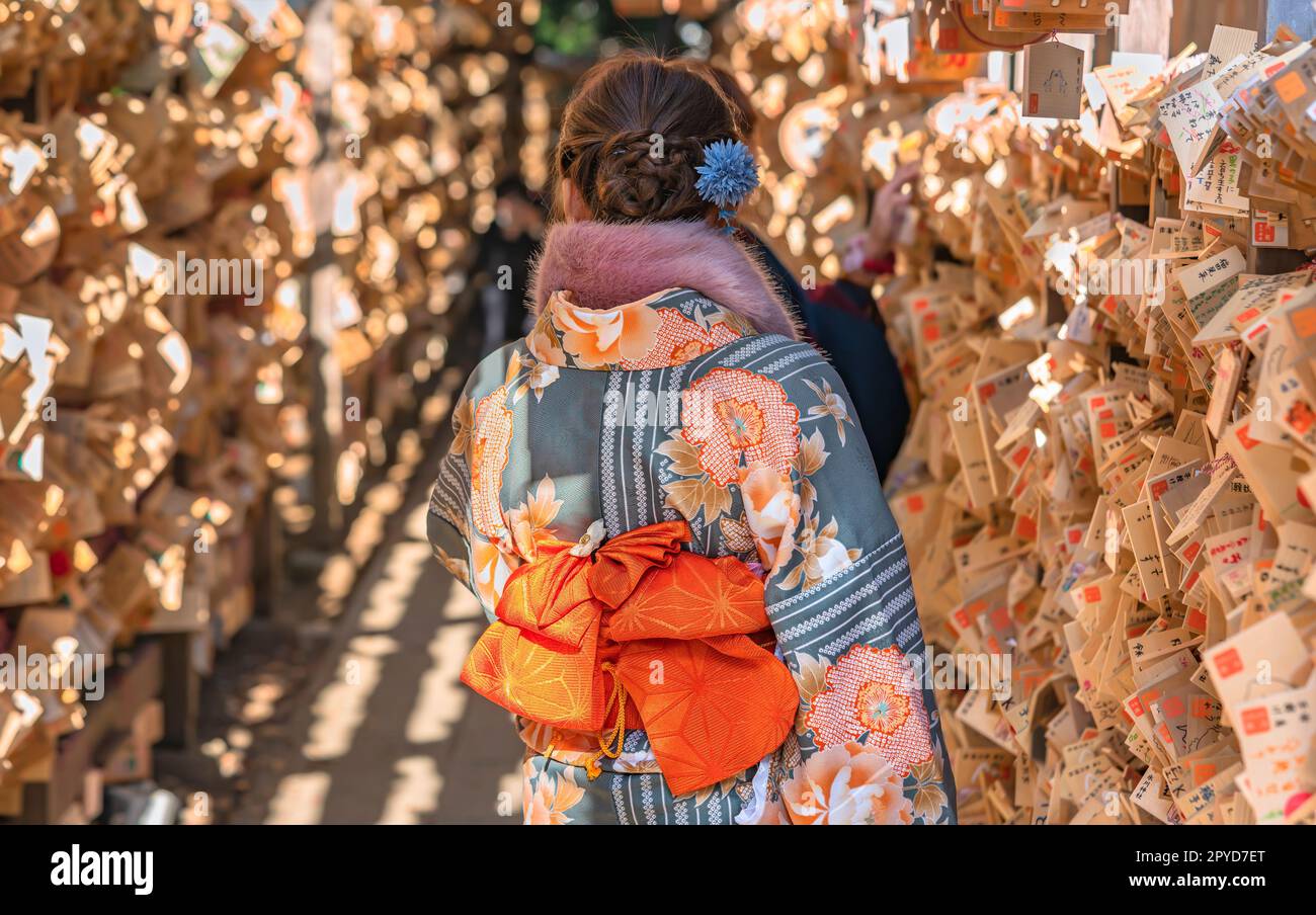 kawagoe, giappone - dicembre 31 2022: Donna giapponese dalla schiena che indossa un kimono invernale con motivi floreali, una cintura obi e una sciarpa di pelliccia in un tunnel di shinto Foto Stock