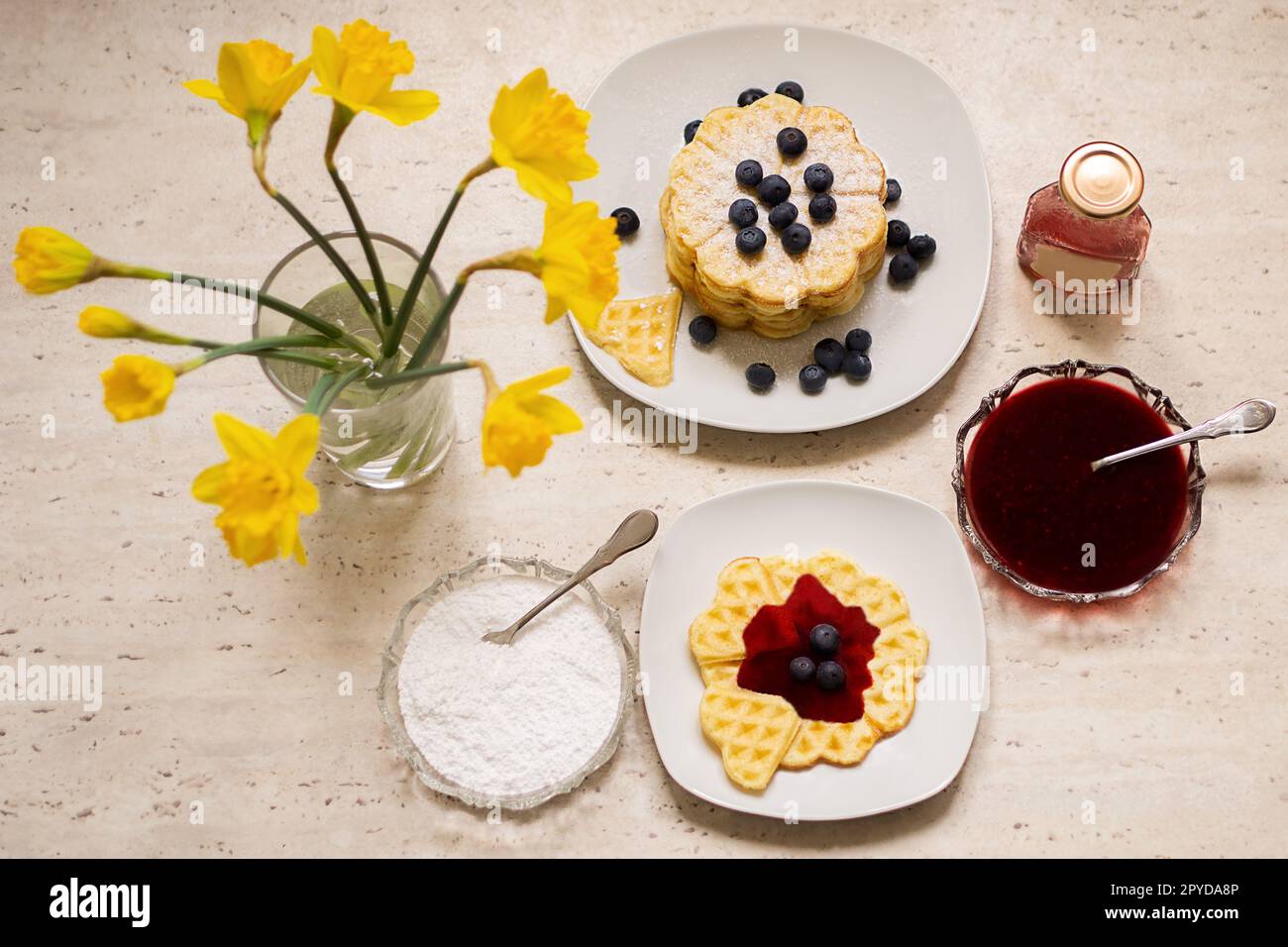 Ottima colazione con un bouquet di fiori e waffle freschi fatti in casa su sfondo bianco. Un regalo per la giornata delle mamme o delle donne. Colazione la mattina presto. Foto di alta qualità. Foto Stock