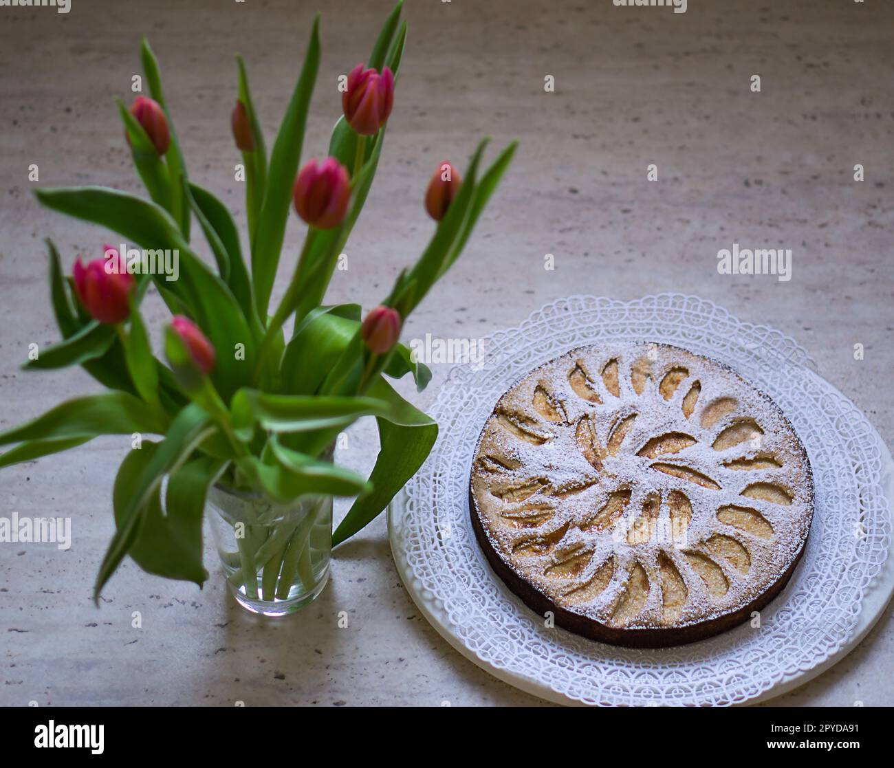 Un bouquet di fiori di tulipani e una torta di mele fatta in casa su uno sfondo bianco. Un regalo per la giornata delle mamme o delle donne. Colazione la mattina presto. Foto di alta qualità. Foto Stock
