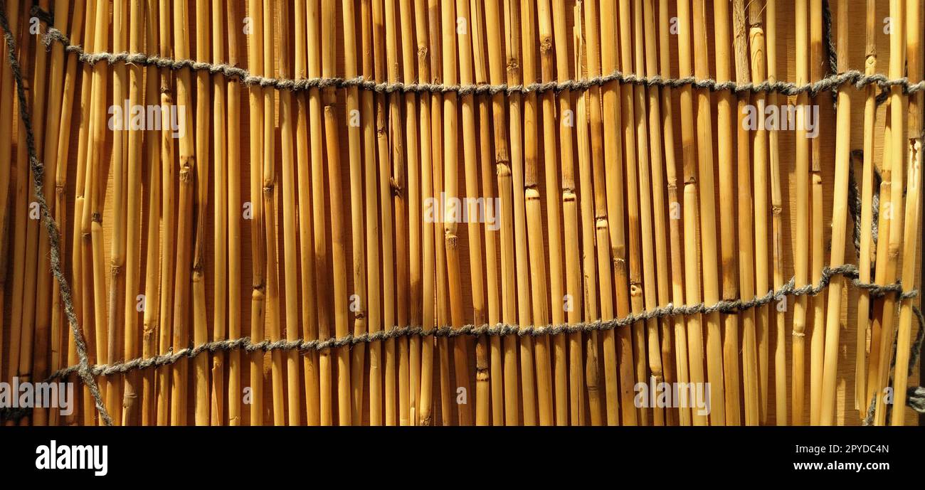 Biancheria da letto in paglia, tovaglia o piccolo tappeto appoggiati sul tavolo. Vista dall'alto dritta. La luce del sole della sera si riflette sui gambi. Alcuni bastoncini sono rotti, fili e funi sono intrecciati Foto Stock