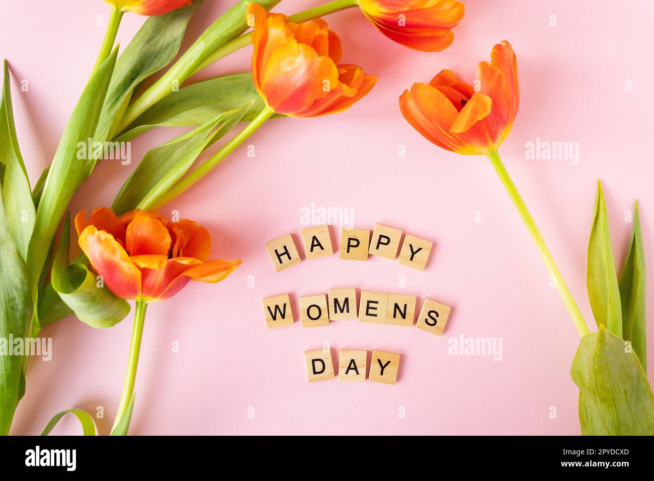 8 marzo, cartolina. Cartello di testo Happy Women's Day con tulipani arancioni su sfondo rosa. Elegante e piatta, con fiori, testo e biglietto d'auguri. Foto Stock