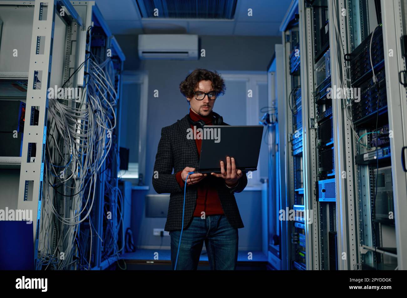 Uomo ESPERTO IT con un notebook che lavora all'aggiornamento del software del data center Foto Stock