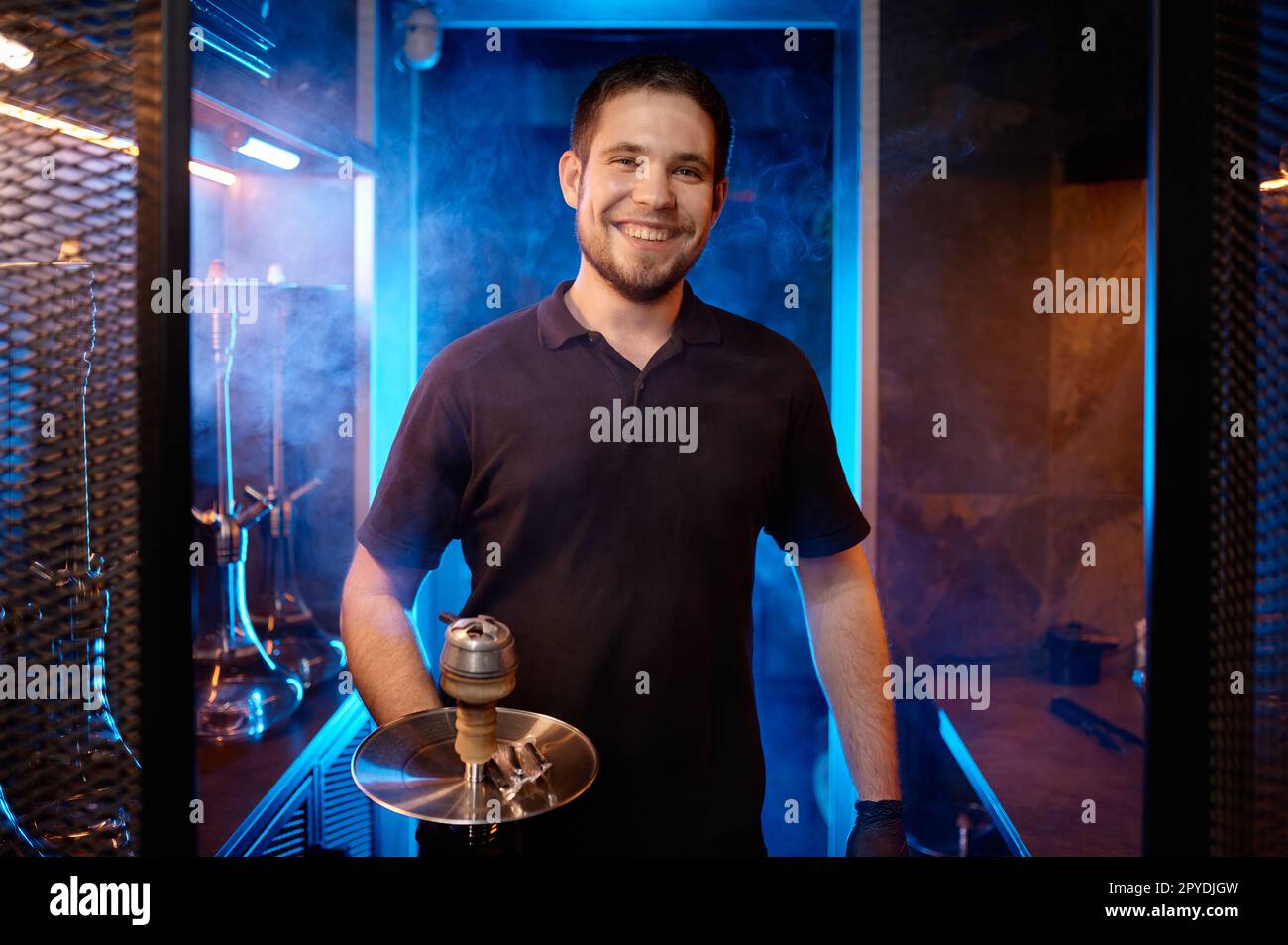 Ritratto di un uomo sorridente con zoccolino che tiene un accessorio orientale tradizionale per fumare Foto Stock